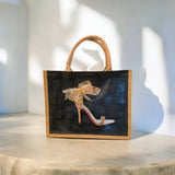 Tan-bordered tote bag featuring a dark front panel with a leopard-print stiletto, red heel, and a sheer bow.