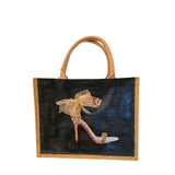 Jute tote with tan handles; black front panel showing a leopard-print stiletto sandal with a sheer beige bow.